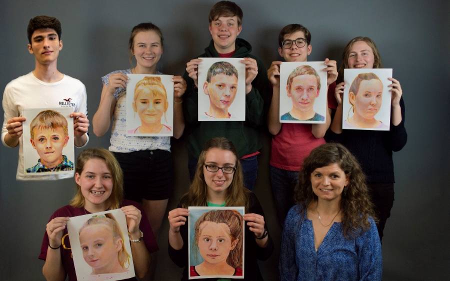 Students holding up their art project drawings