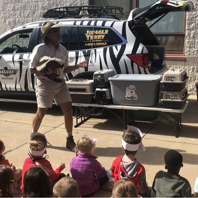 Jungle Terry holding a skunk for Elementary students