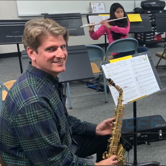 Band Teacher with Student Playing Instrument in Background