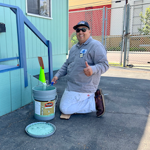 EUSD painter kneeling while painting a school building