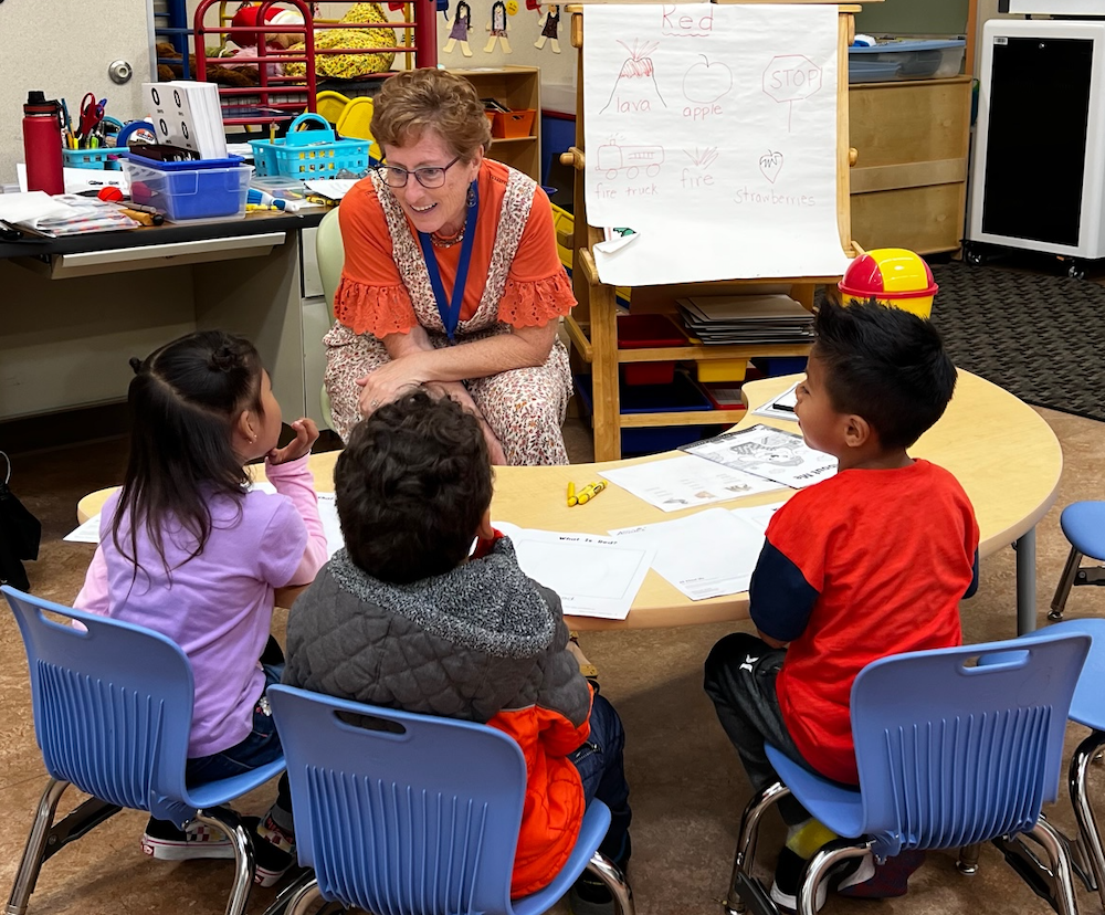 TK teacher talking to her students at a table in class