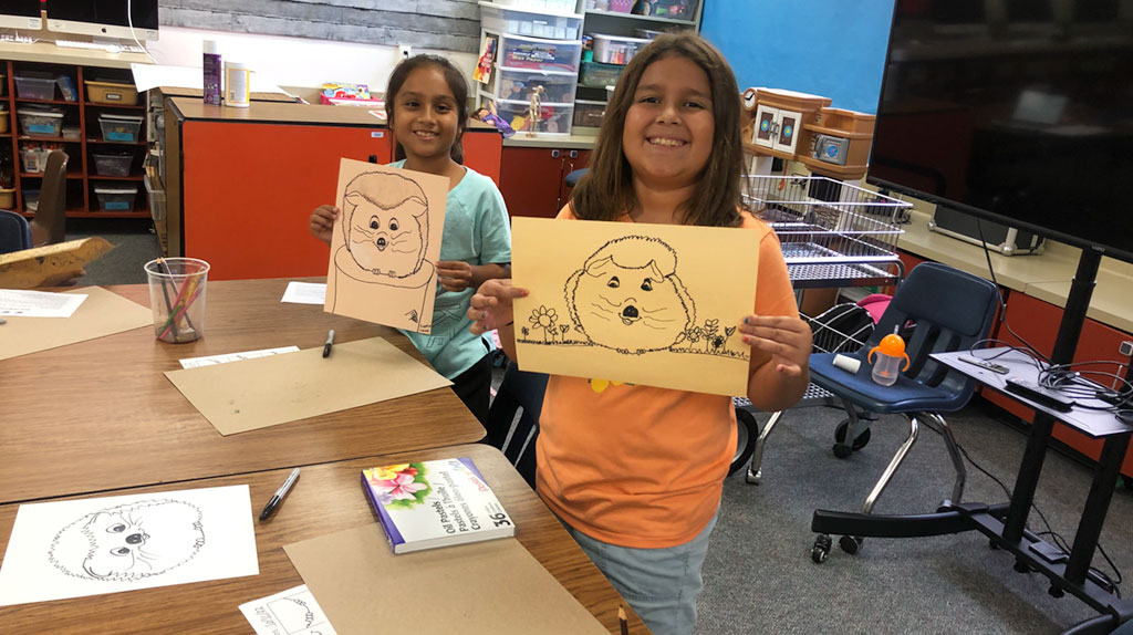 Two student holding their artwork