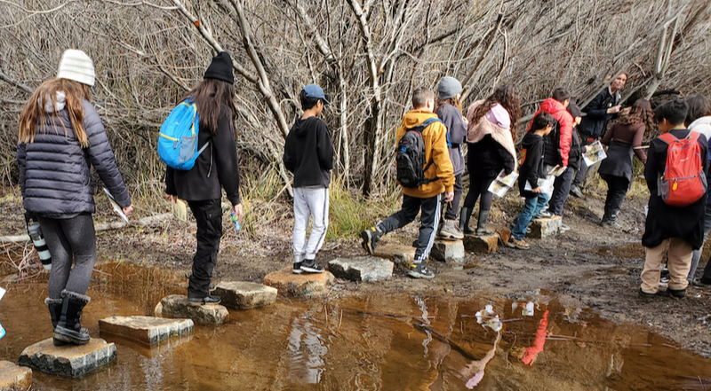 Students walking across stones at camp