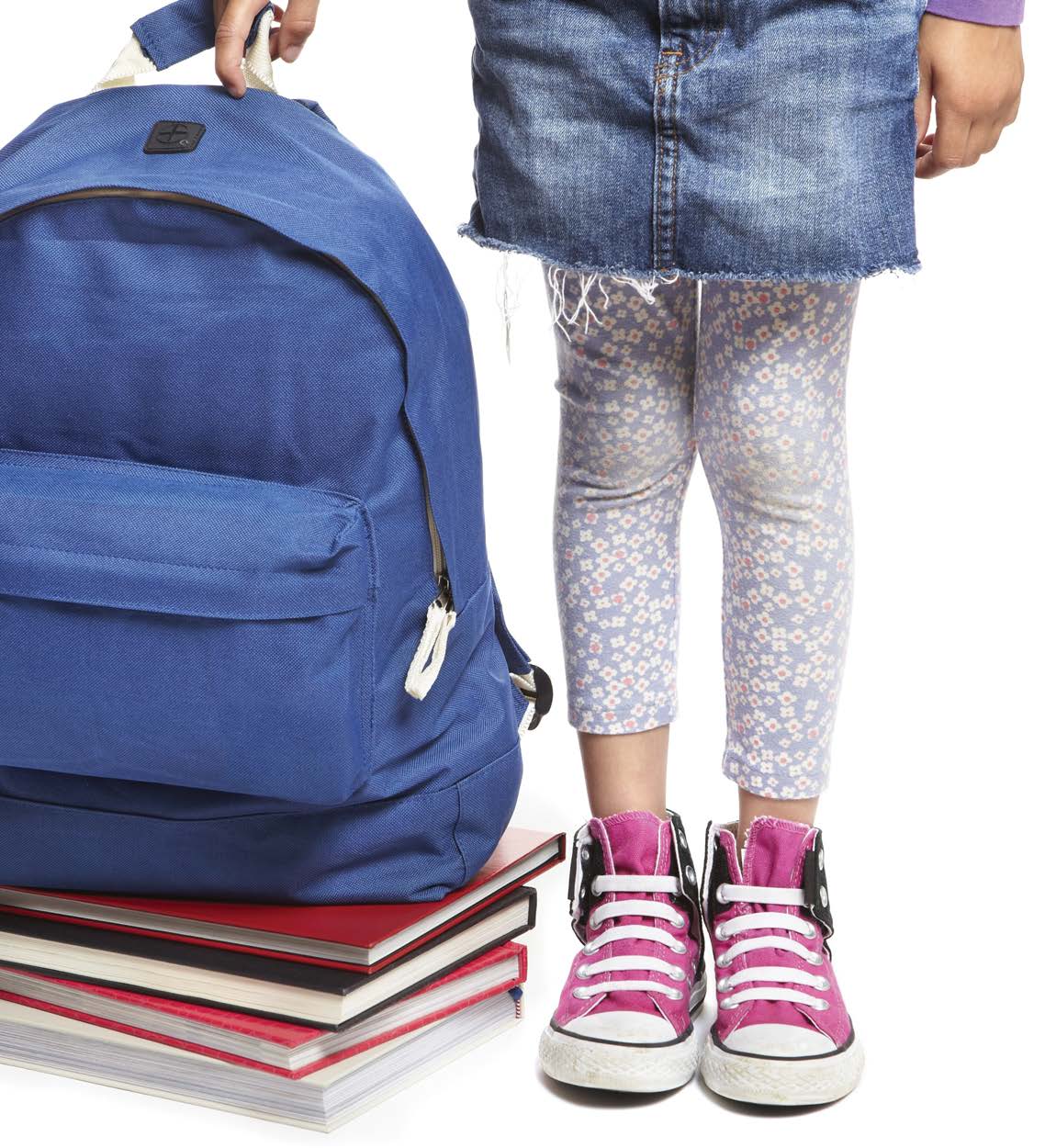 Girl holding backpack in one hand on top of a stack of books