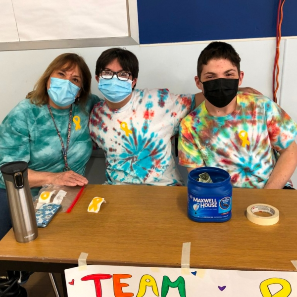 Two High School students sitting with Teacher collecting money for "Team Matthew" - A charitable event