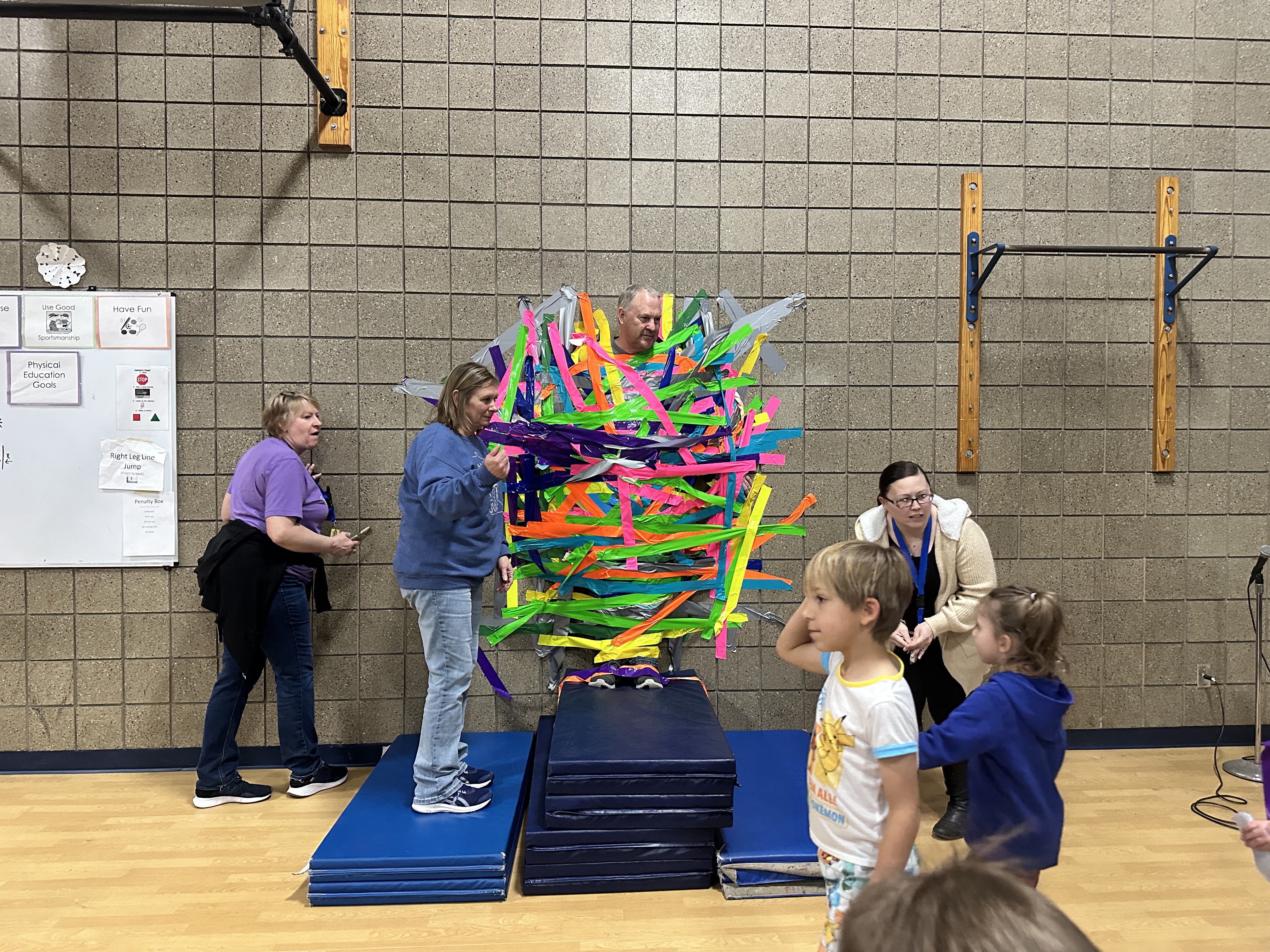 students taping principal to brick wall