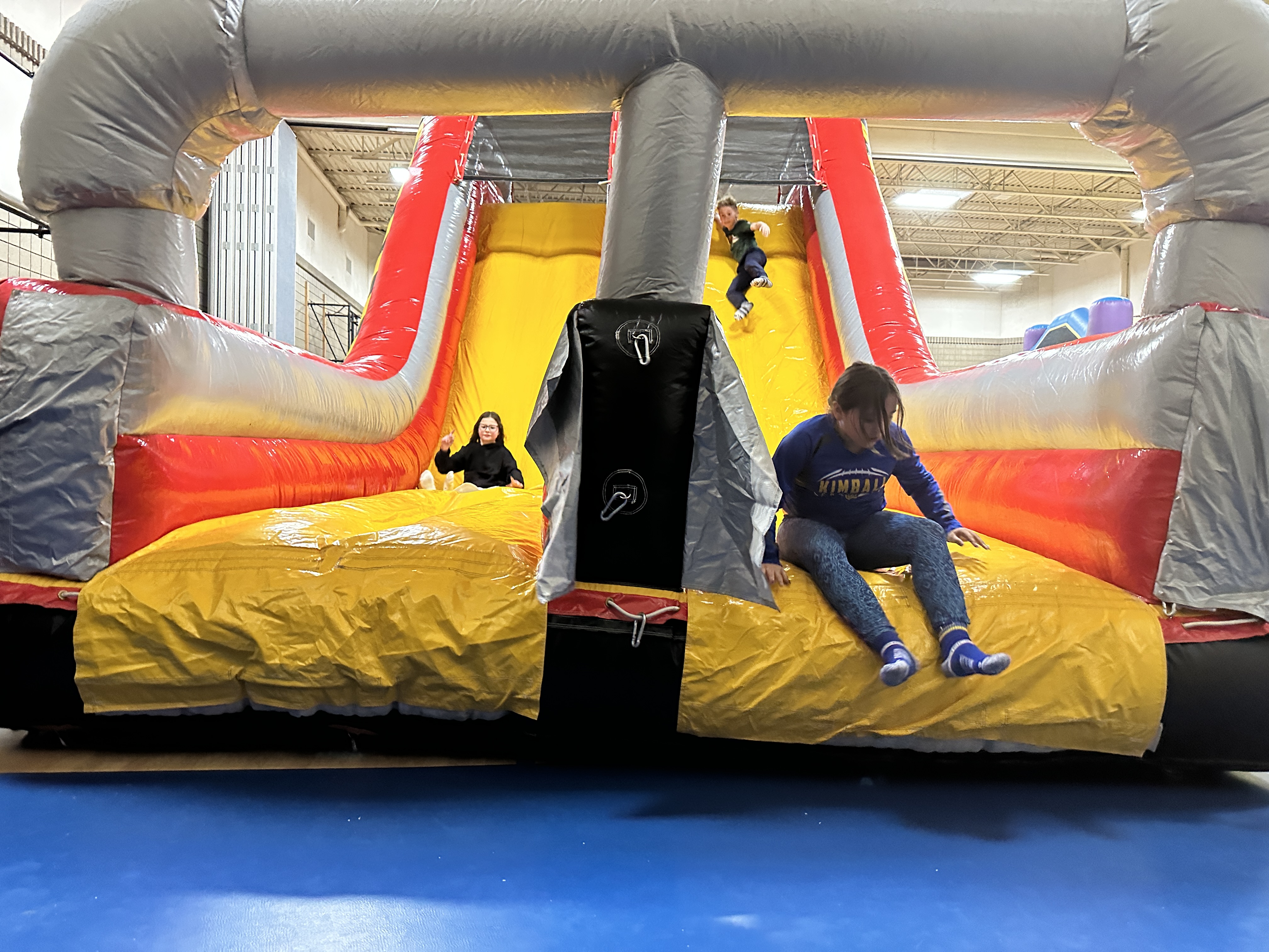 students going down yellow inflatable slide