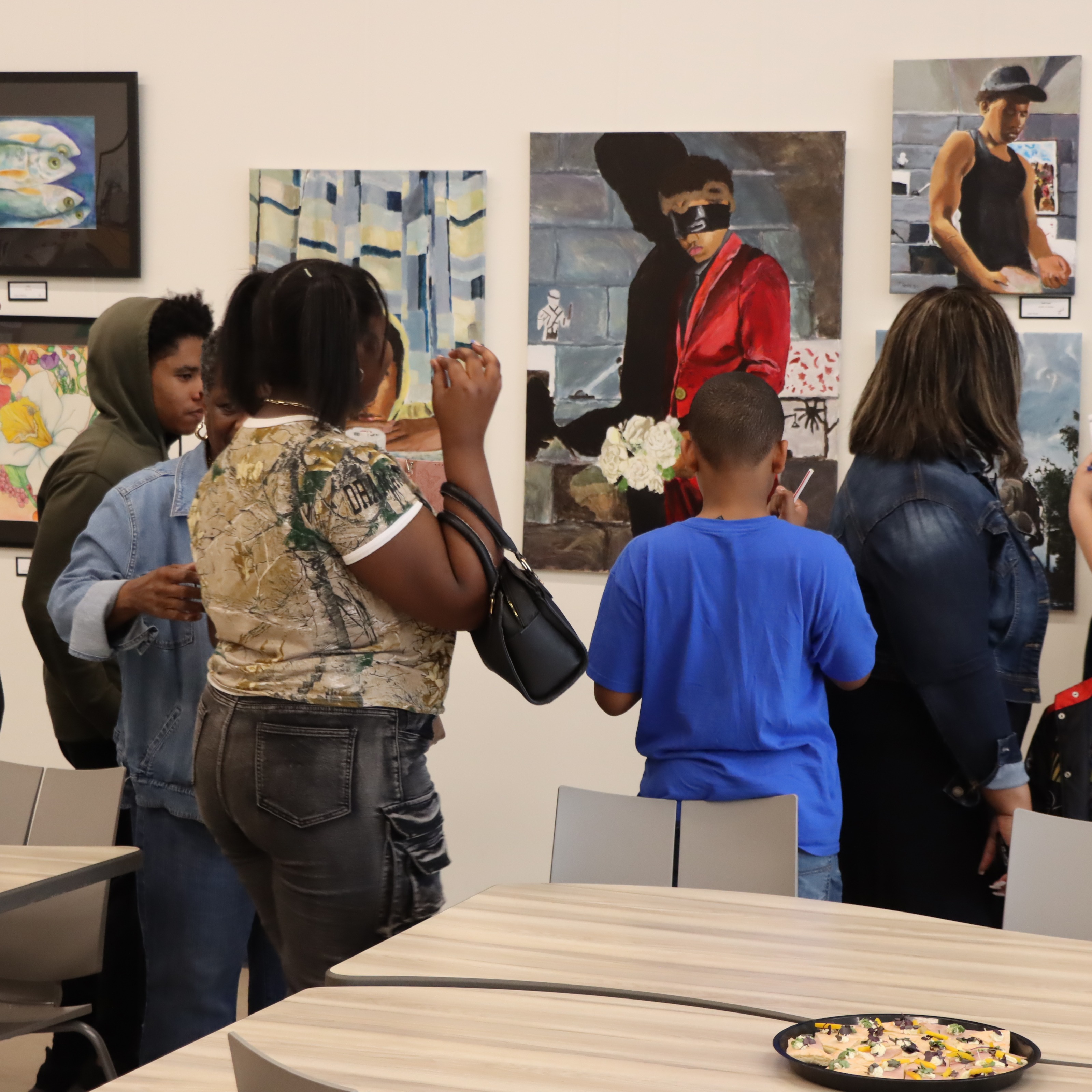 Patrons at the Senior Art Show, reviewing student art that was hung in the Culinary Bistro.