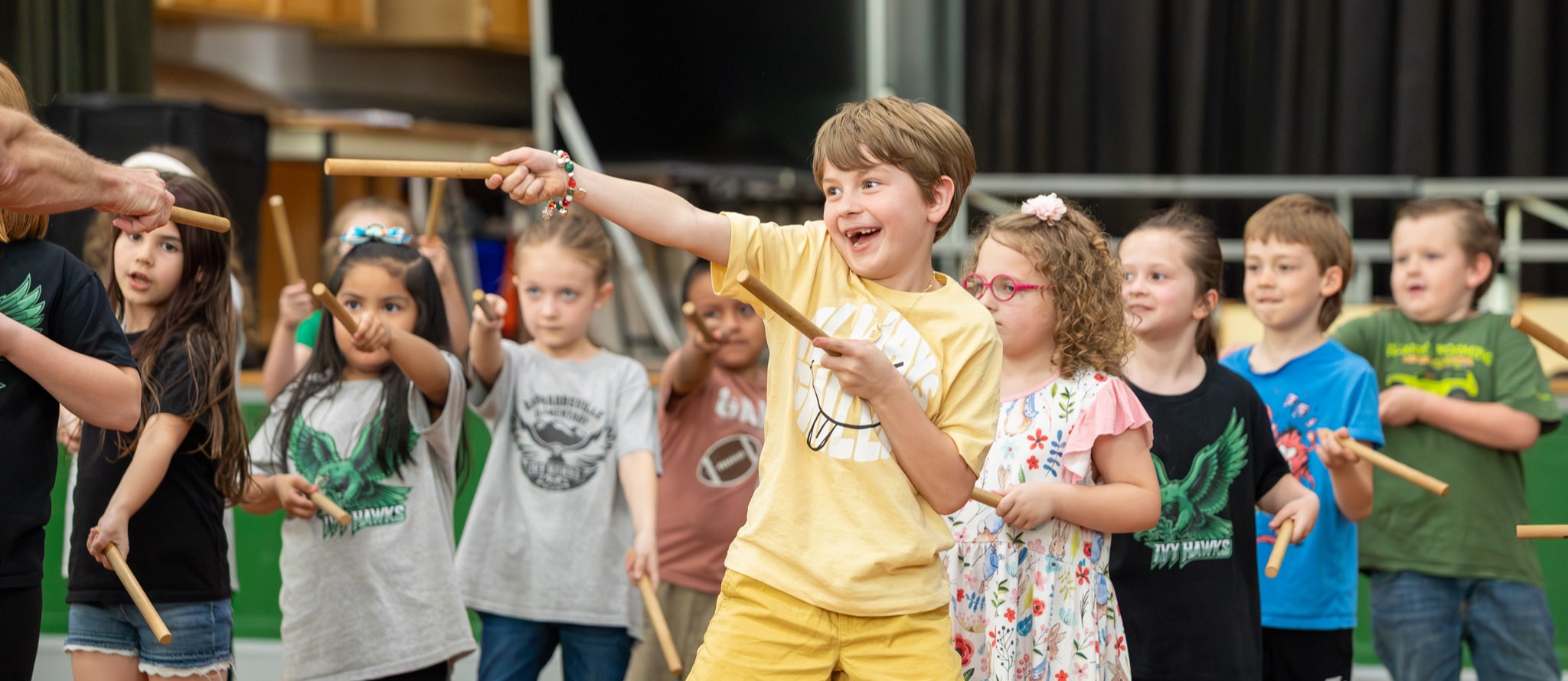Students smile and point noise sticks during a Spring Arts Day performance.