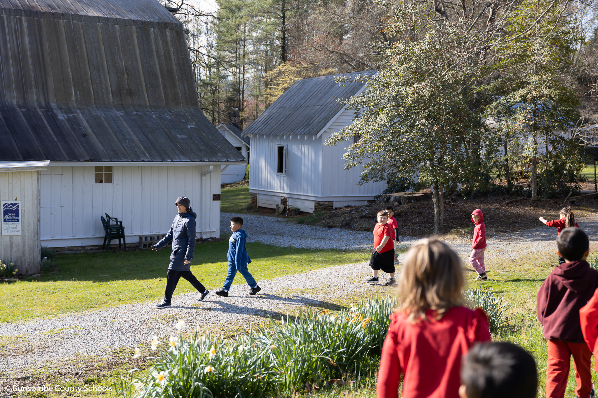 Kindergarten students being led by a tour guide through the property of the Historic Johnson Farm. 