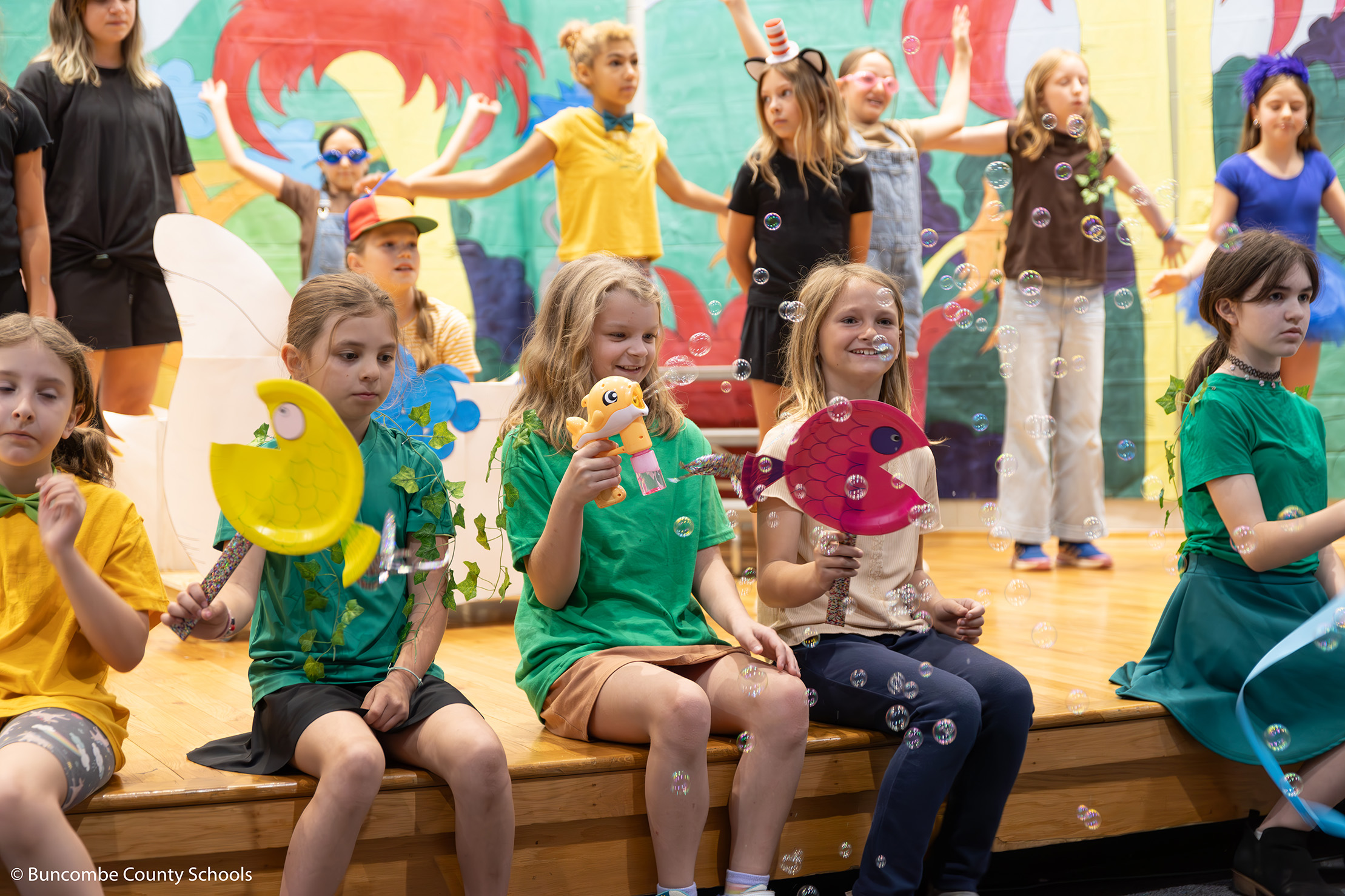 Students singing in the Suesical musical production with bubbles blowing in the air. 
