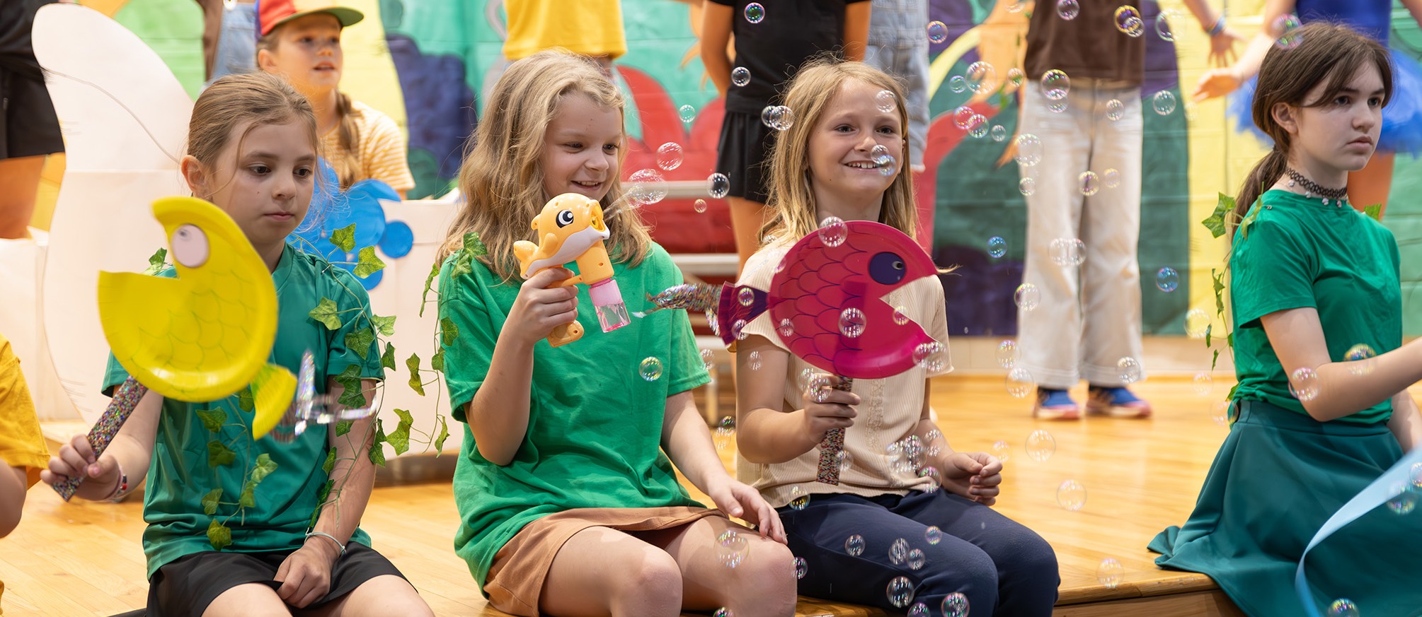 Students singing in the Suesical musical production with bubbles blowing in the air. 