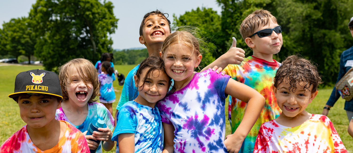 A group of students wearing tie-dyed shirts and smiling.