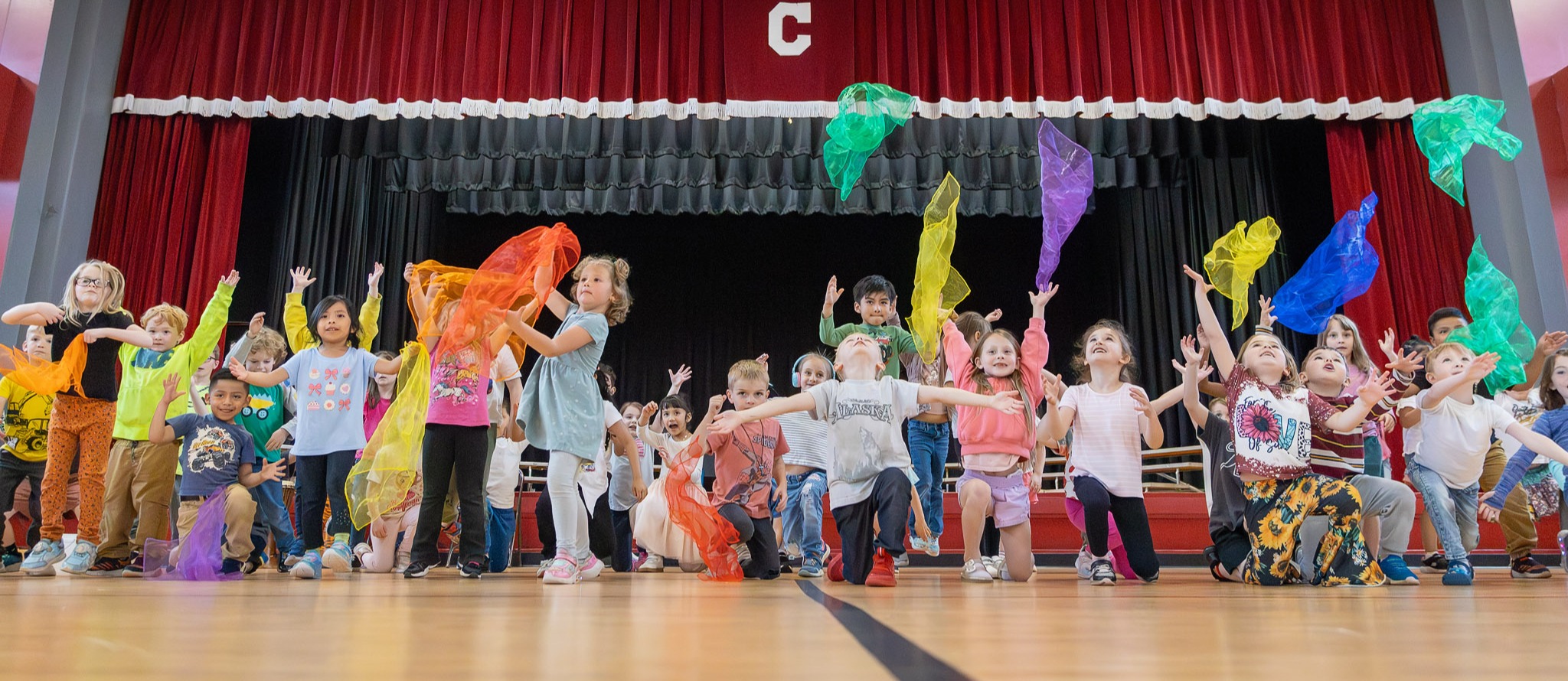 Kindergarteners throw colorful fabric into the air during a Global Day performance.