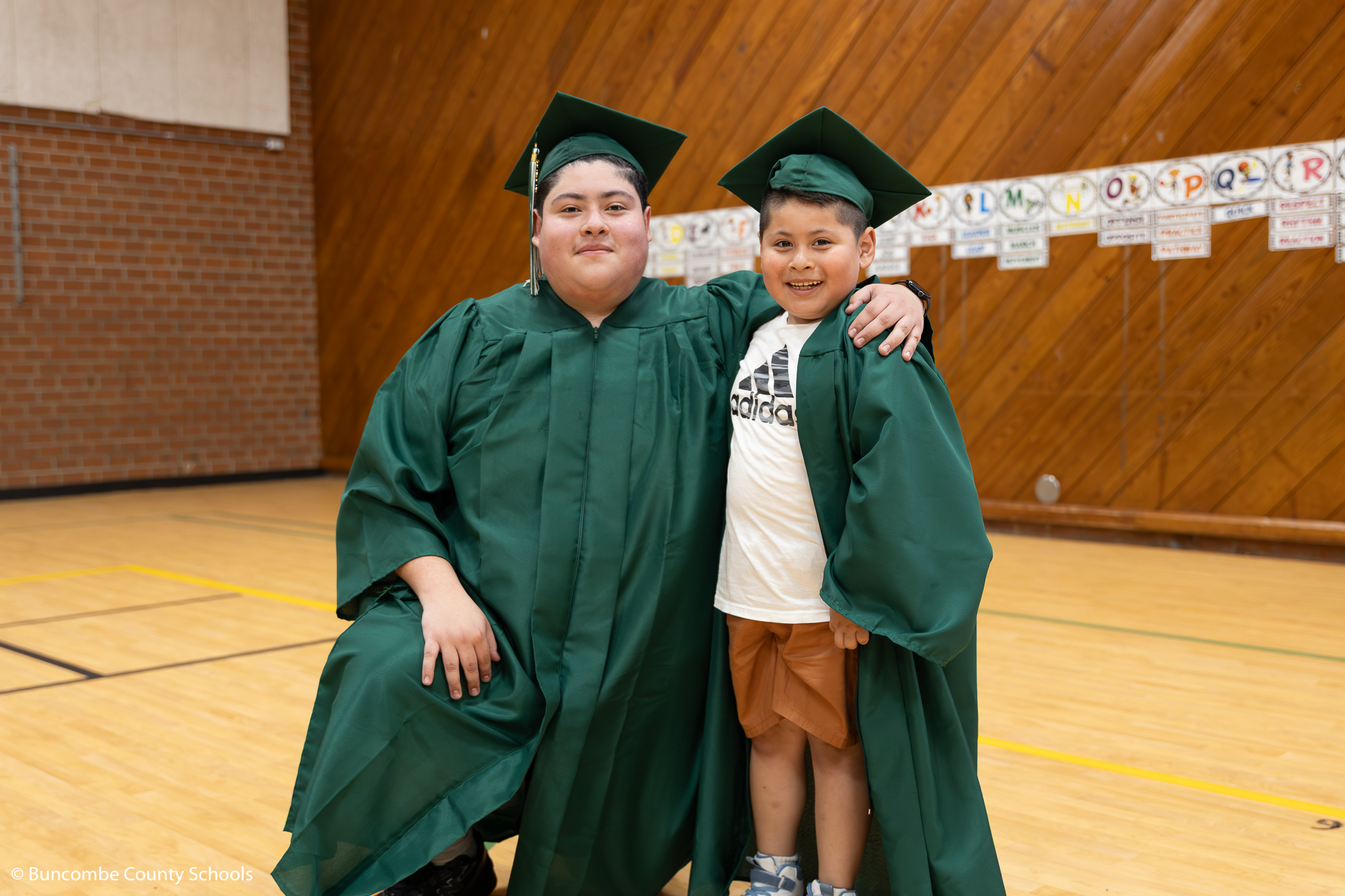 Senior in a cap and gown beside a Haw Creek student in a cap and gown.