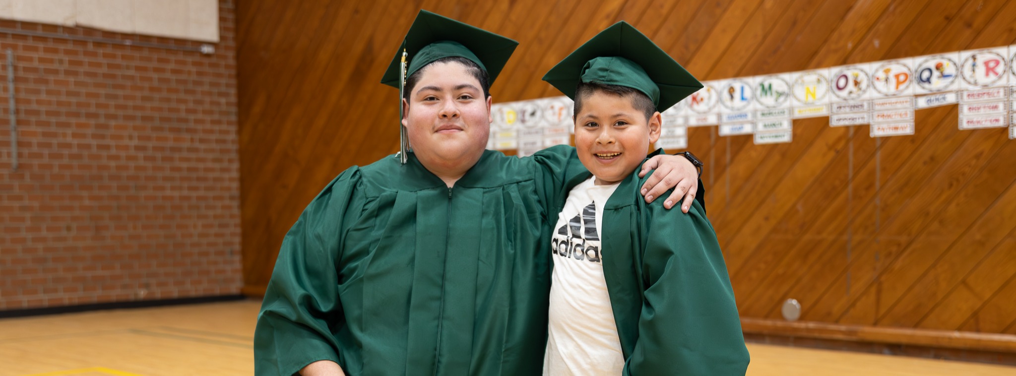 Senior in a cap and gown beside a Haw Creek student in a cap and gown.