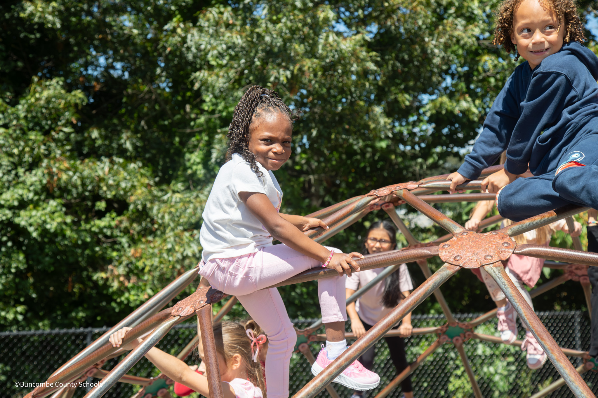 Little girl sitting on the climbing dome on the playground. 