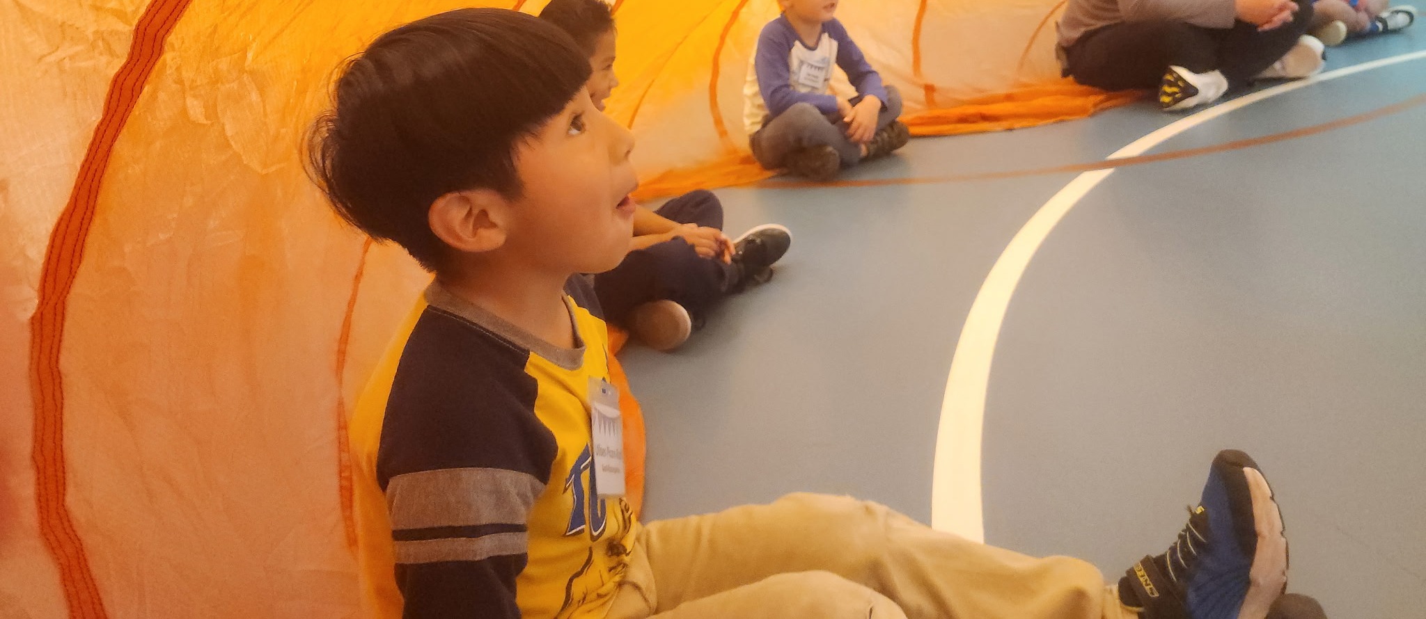 Little boy sitting under a parachute.