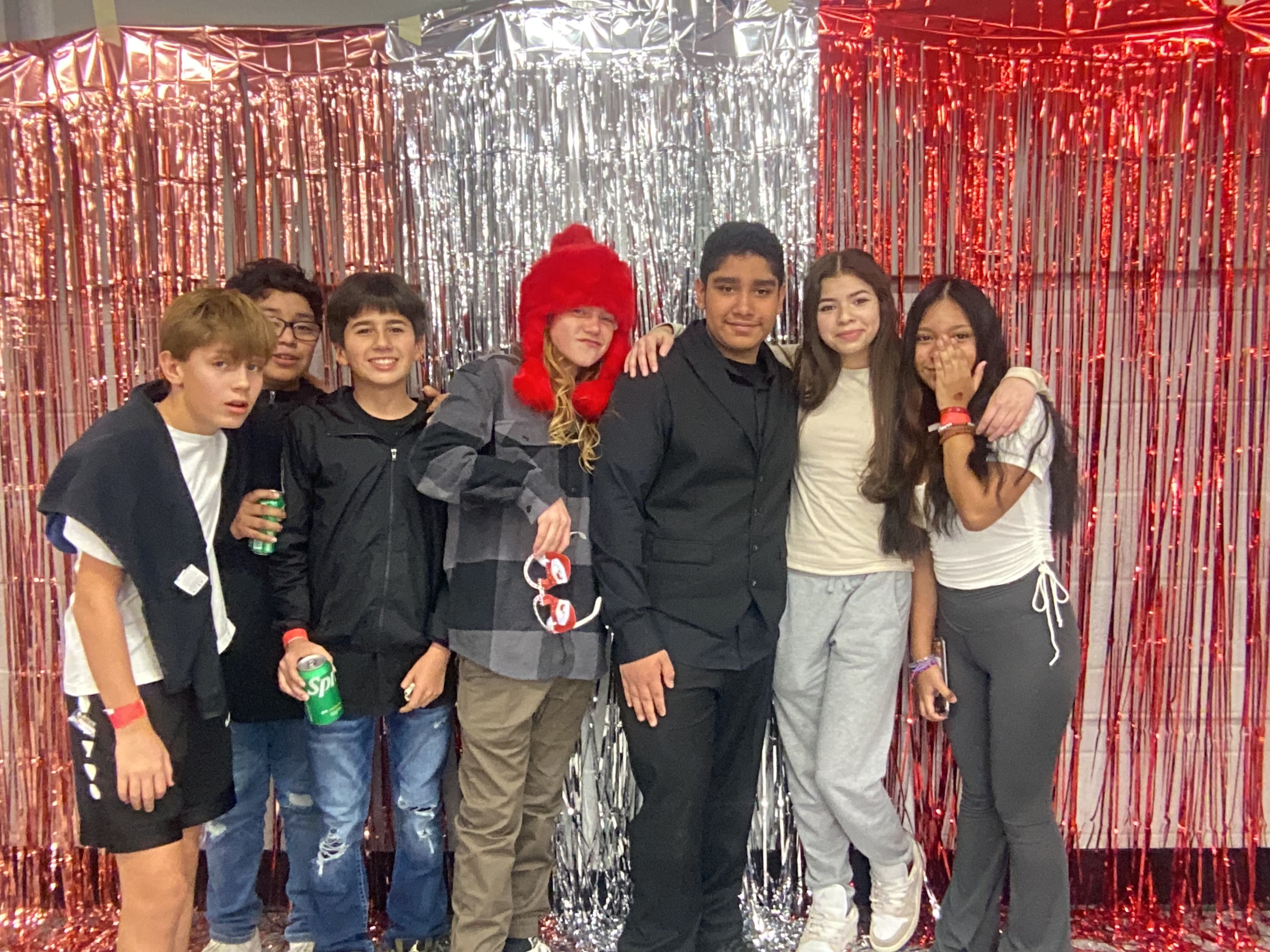 students at a school dance in front of a streamer background