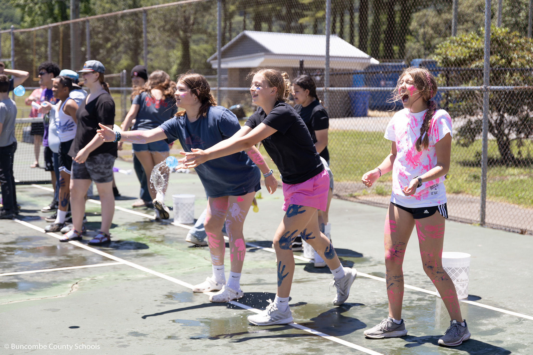 Group of female students throwing water balloons at field day. 