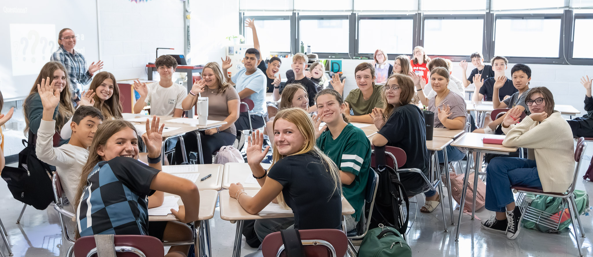 A classroom full of students waving.
