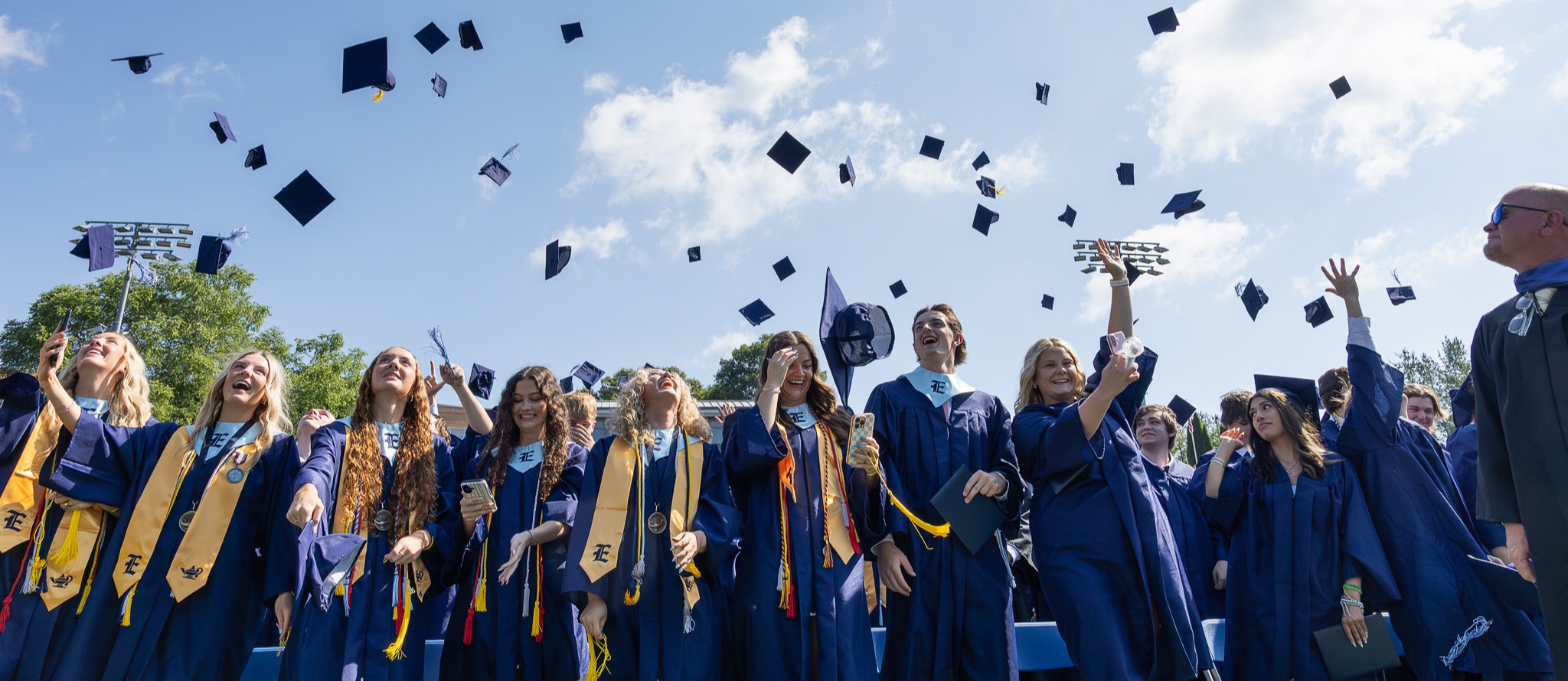 Graduates from the Class of 2026 throw their caps into the air.