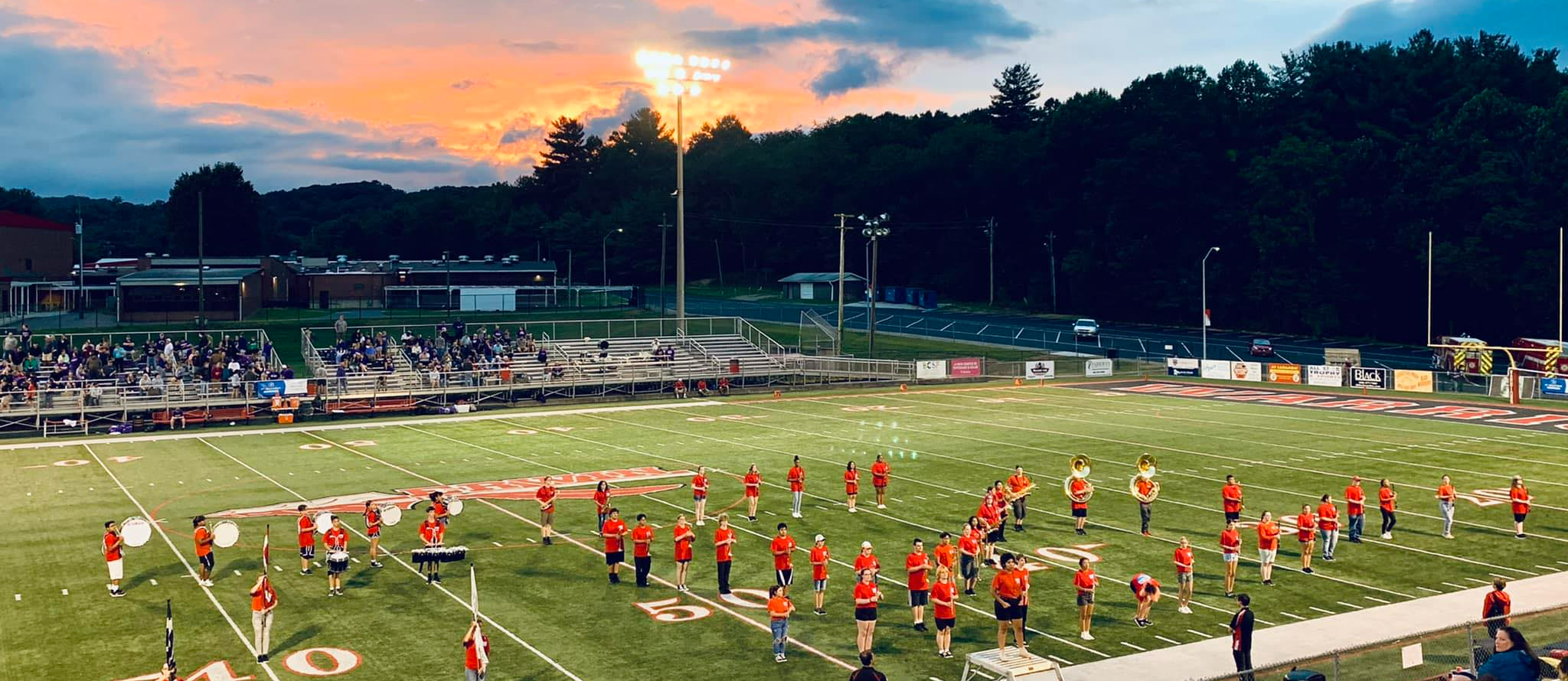 Marching band on the football field during a sunrise.