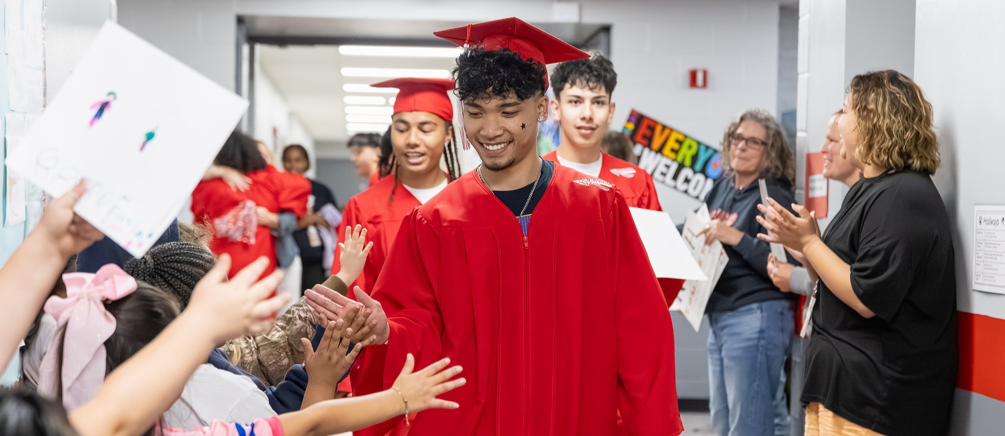 Erwin seniors, dressed in caps and gowns, high-five students at Johnston Elementary.