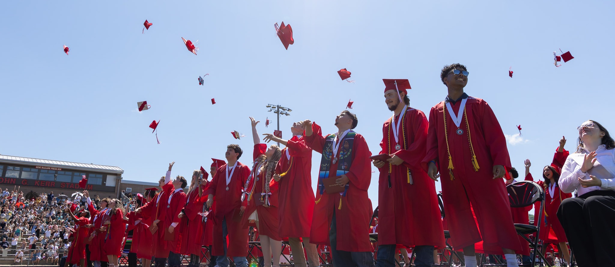 Erwin seniors, dressed in caps and gowns, throw hats into the air.