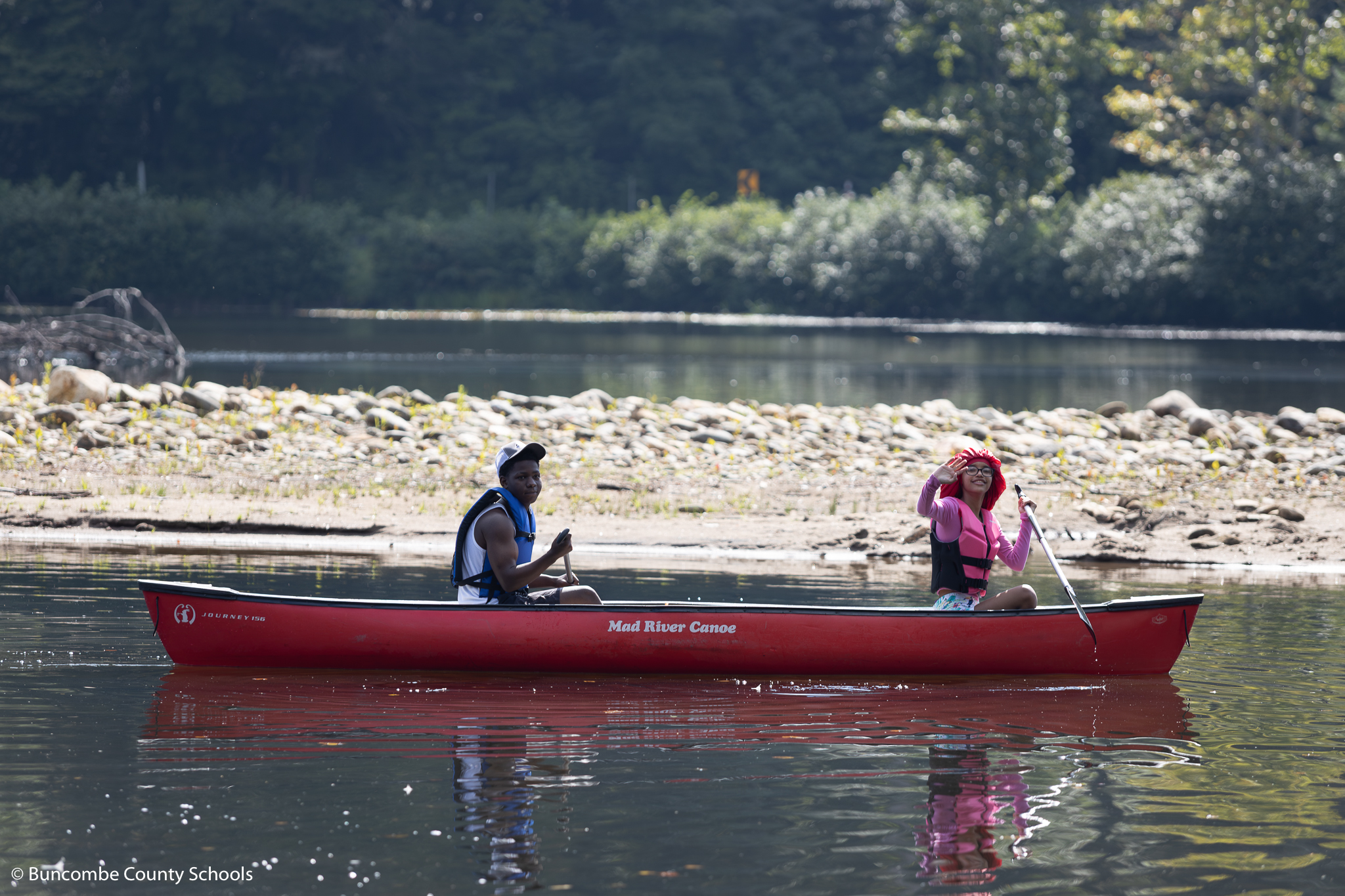 Two students in a canoe looking at the camera smiling. 