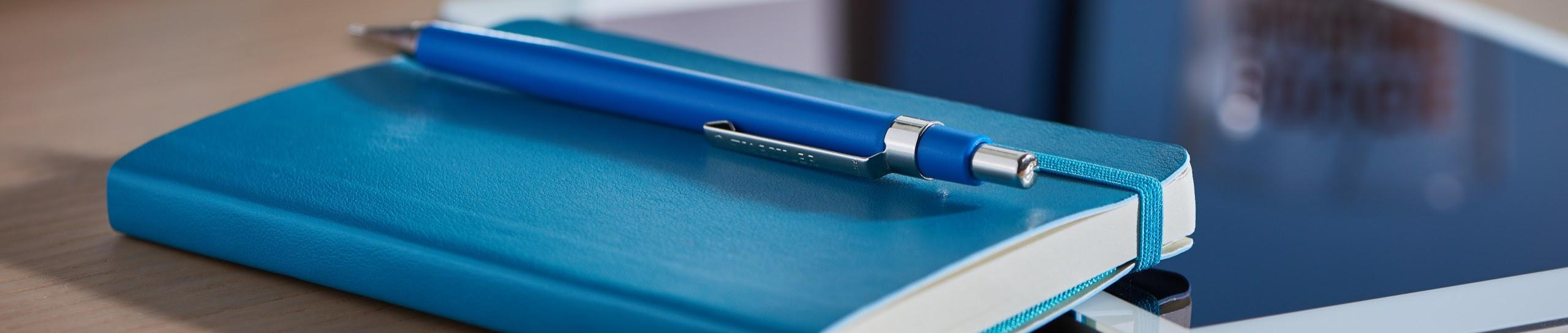 Blue notebook, pen and tablet on a table