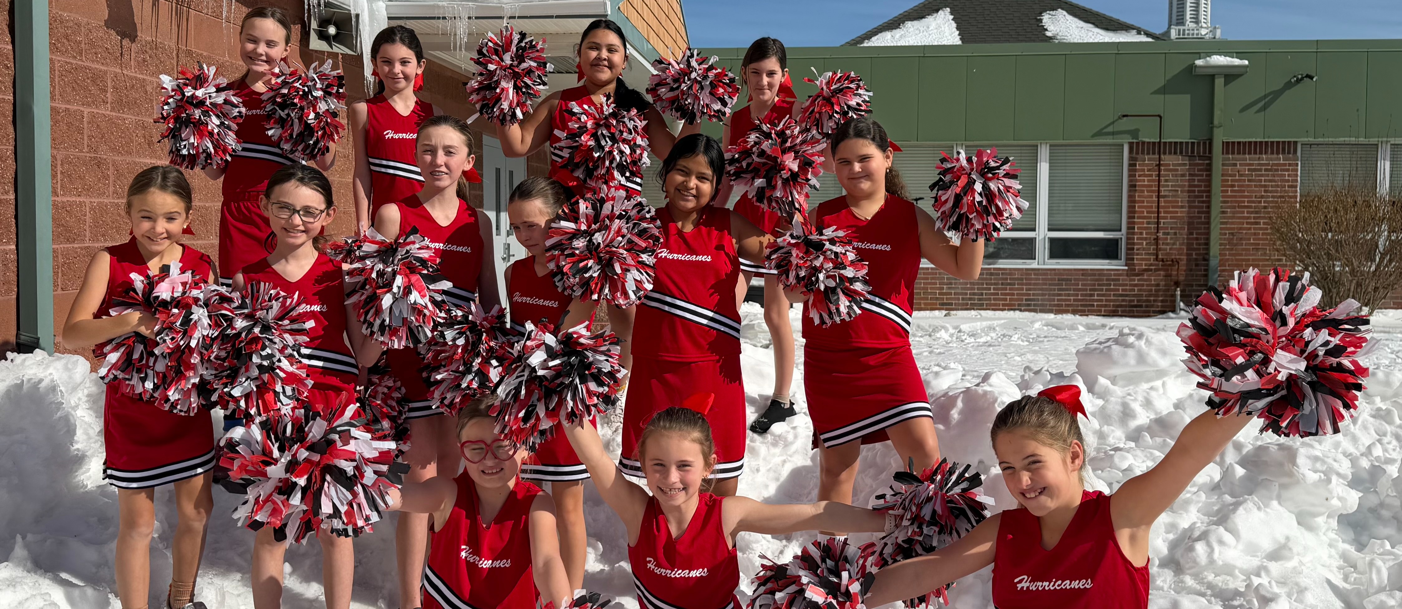 Cheerleaders outside smiling in the snow