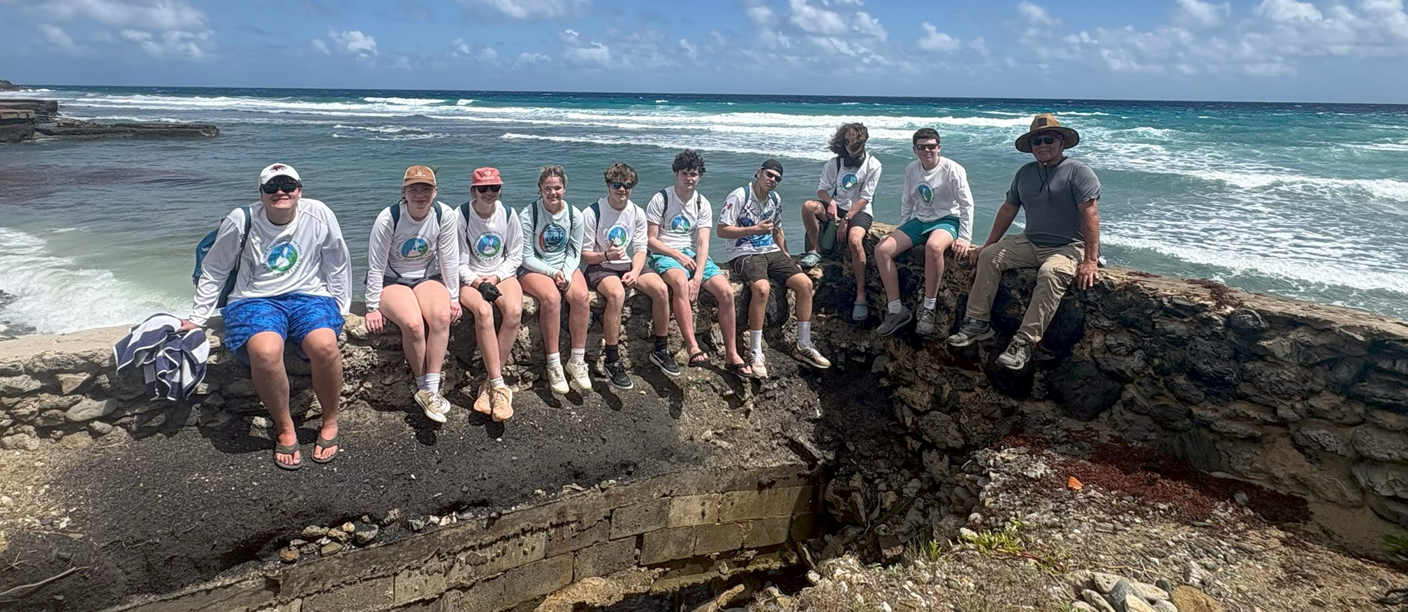 A group of students sitting on a sea wall.