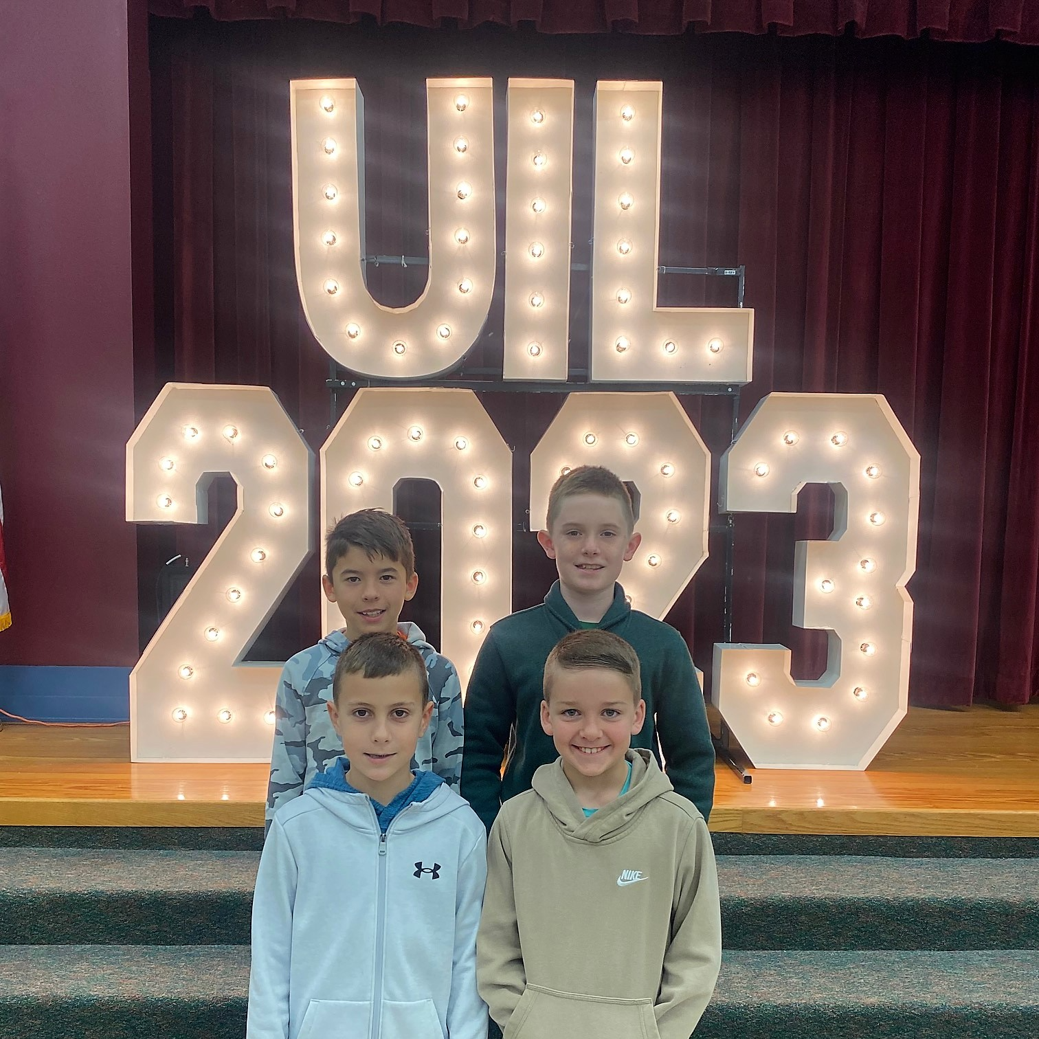 4 male students in front of UIL 2023 large lights and numbers