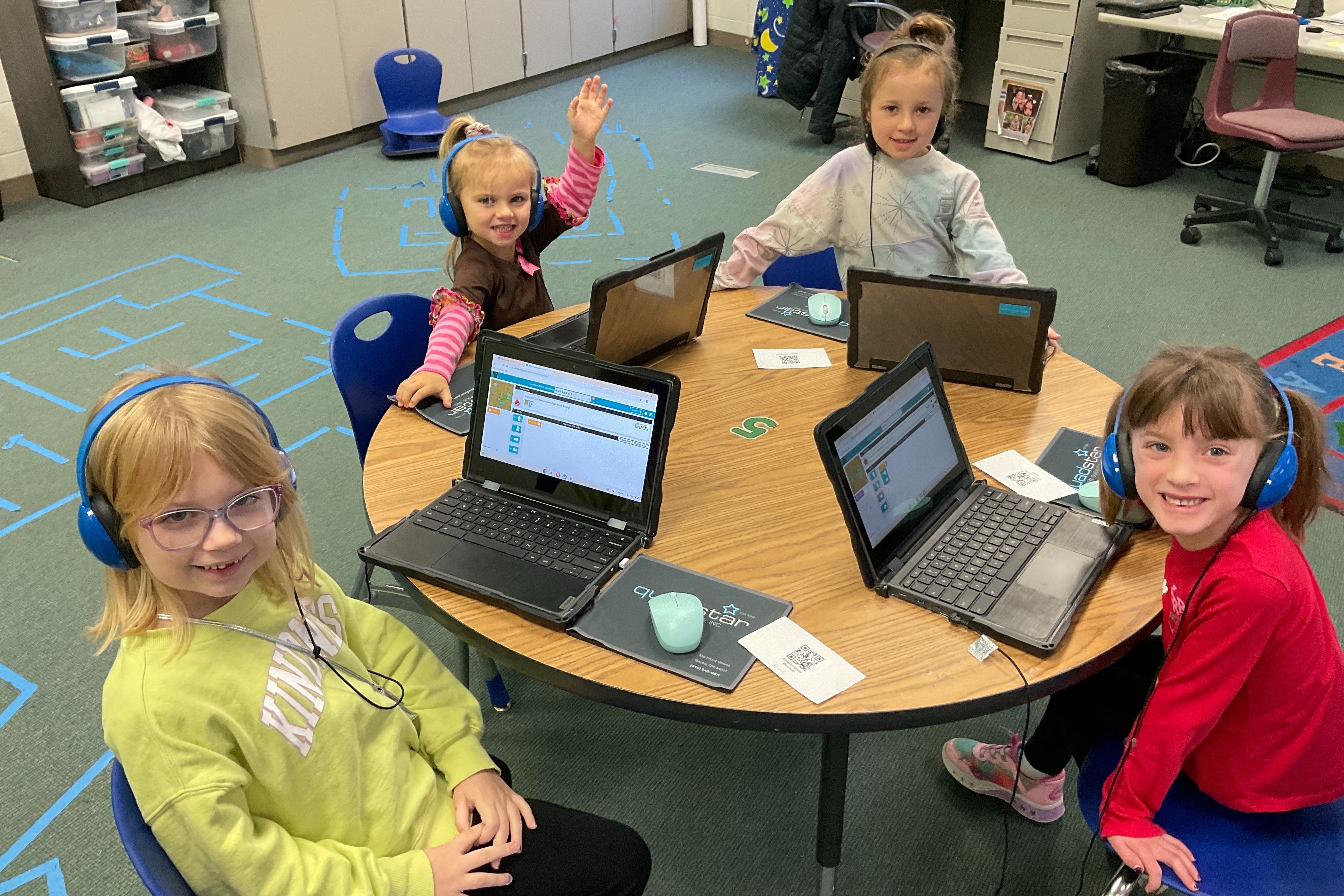 students at a table working on computers with headphones on