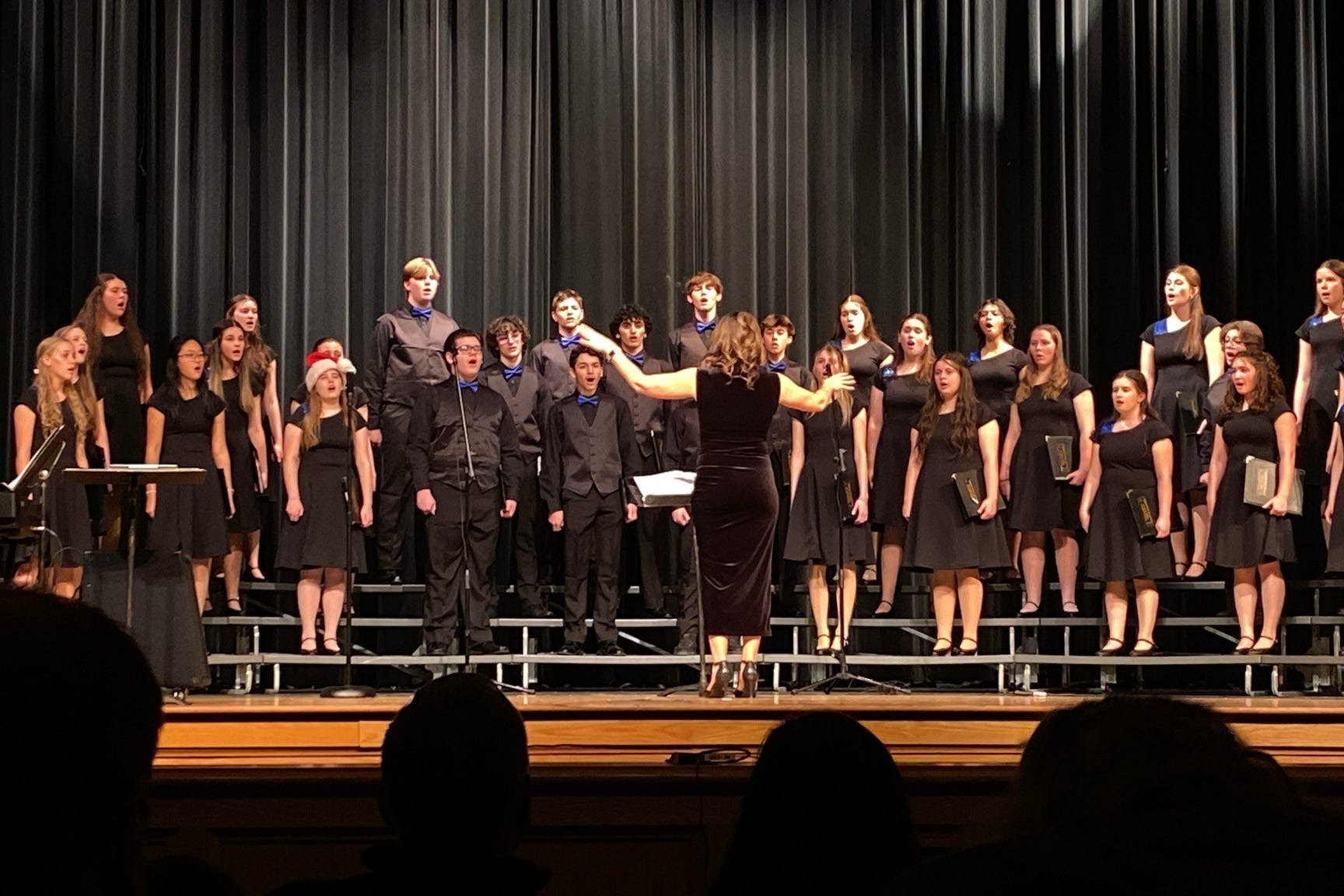 high school choir members singing on stage in the auditorium