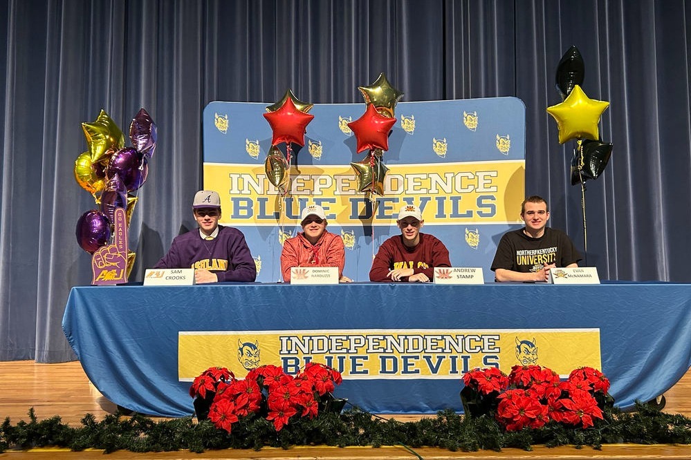 four student athletes at a table during signing day at the high school
