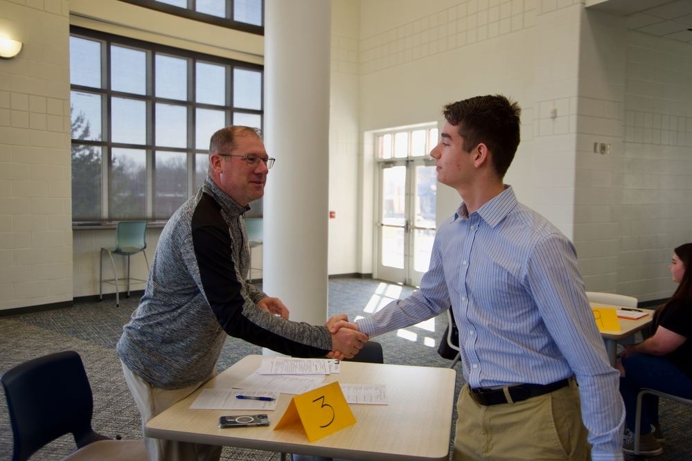 an administrator shaking hands with a high school student during mock interview day