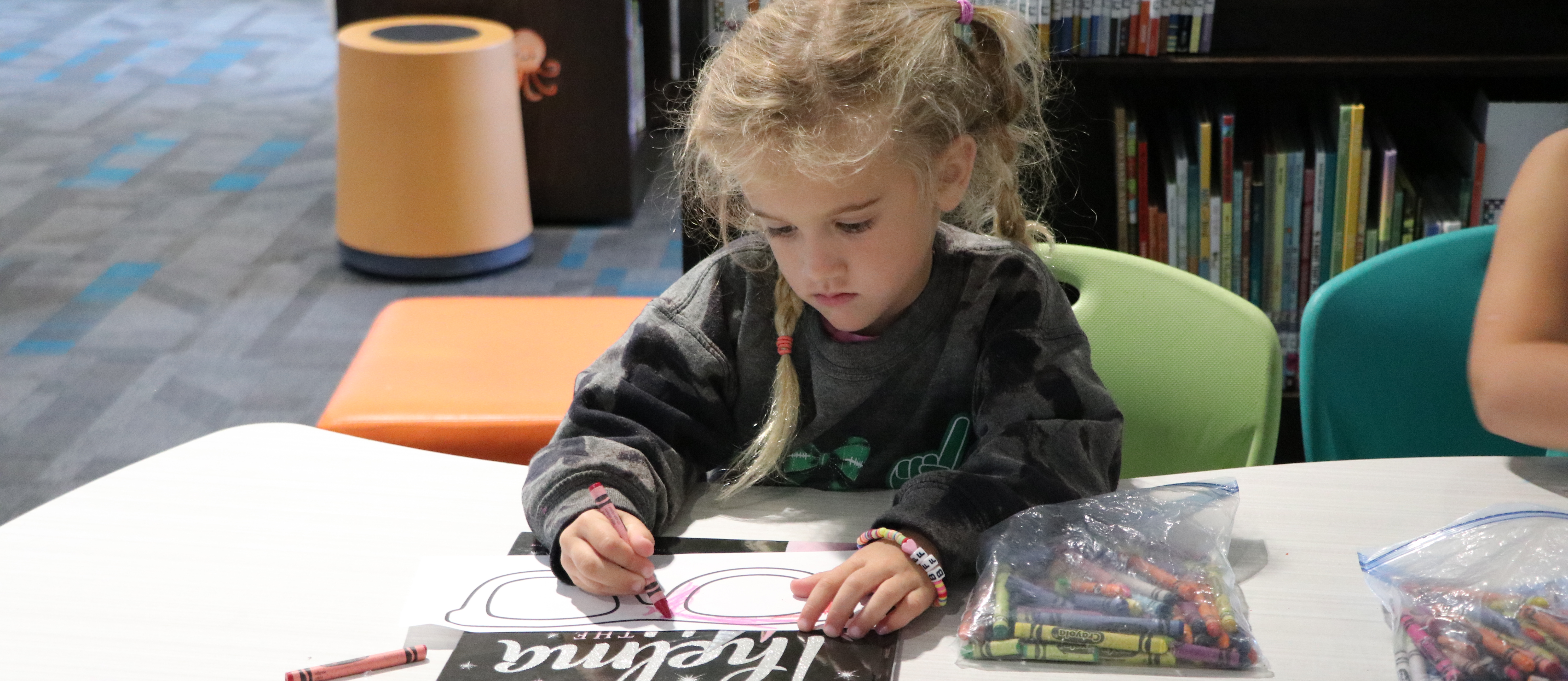 Kindergarten girl is coloring in the library