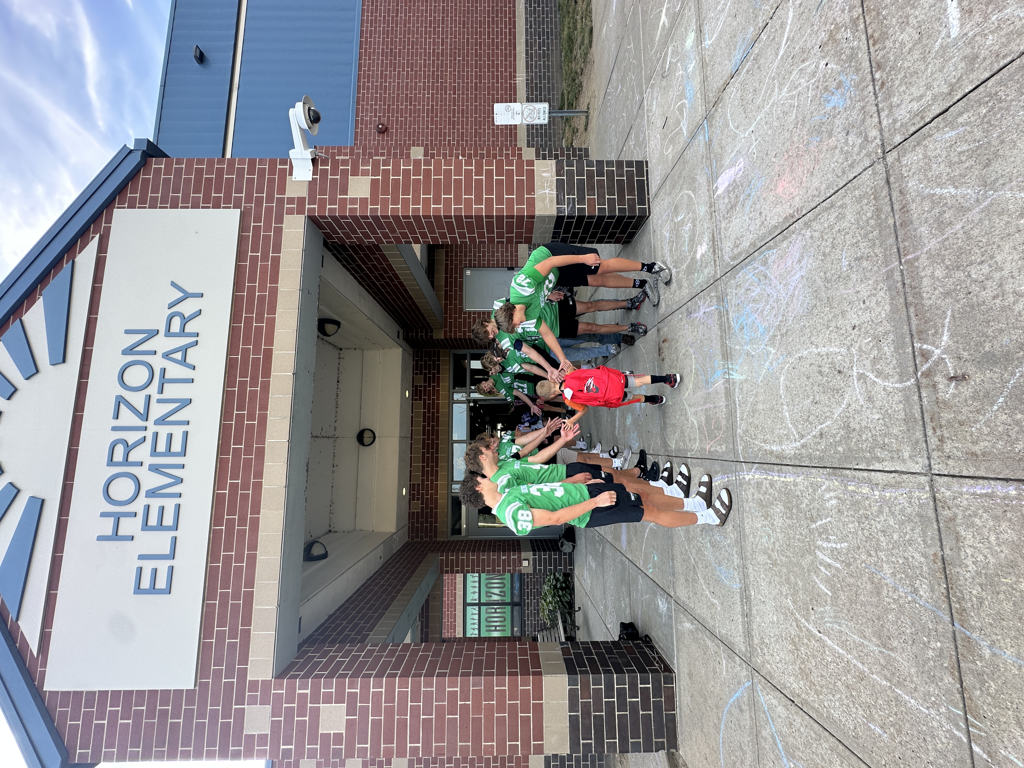 Football players line up in front of the school to greet elementary students