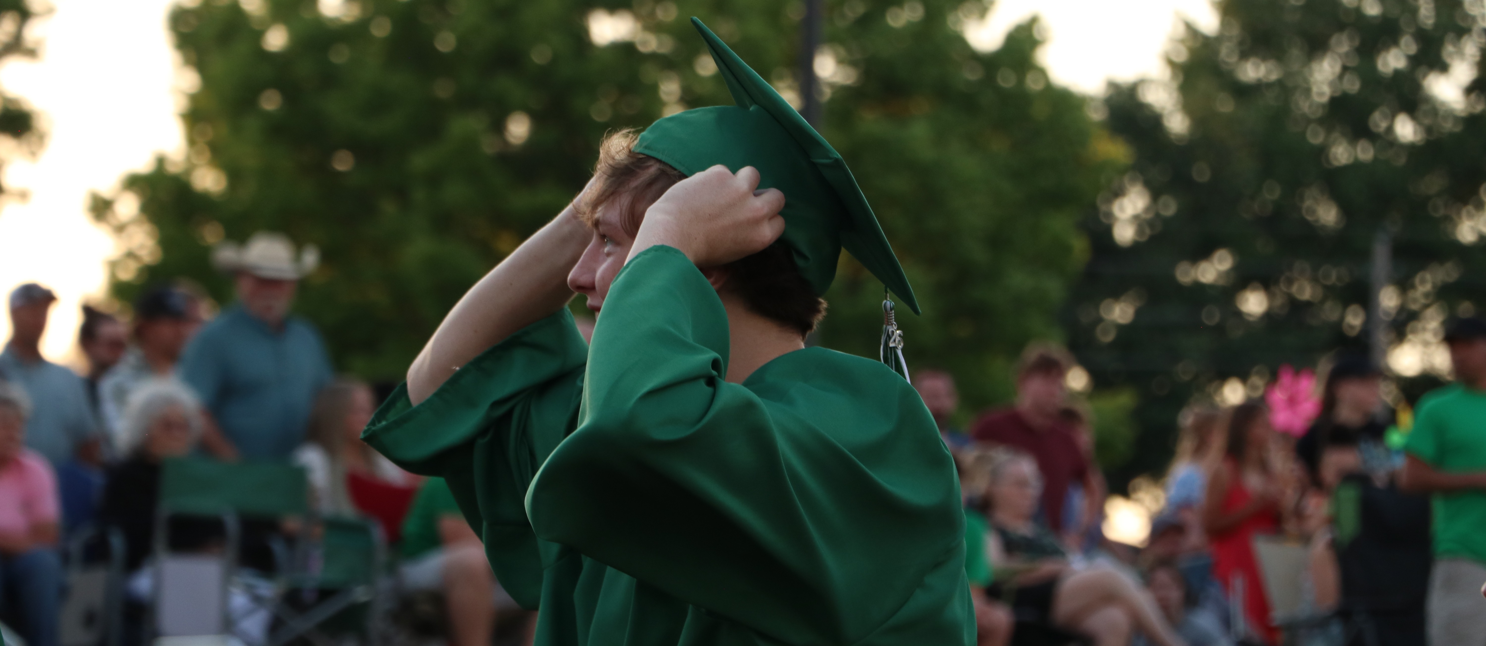 A graduate pulls his hat on as he walks onto the field