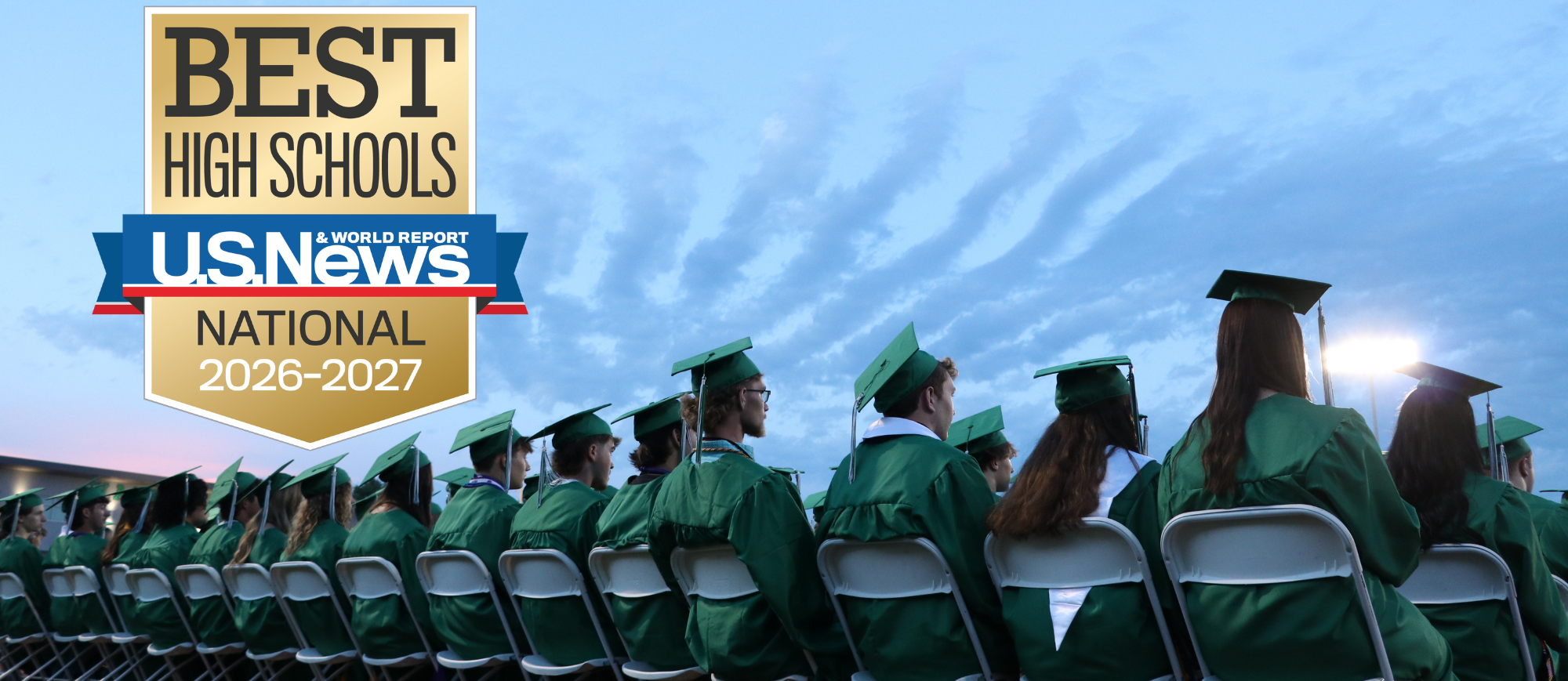 High School graduates sitting in their chairs at graduation with interesting clouds in the sky beyond them. in the corner is a badge that says US News and World Report Best High Schools 2026-2027