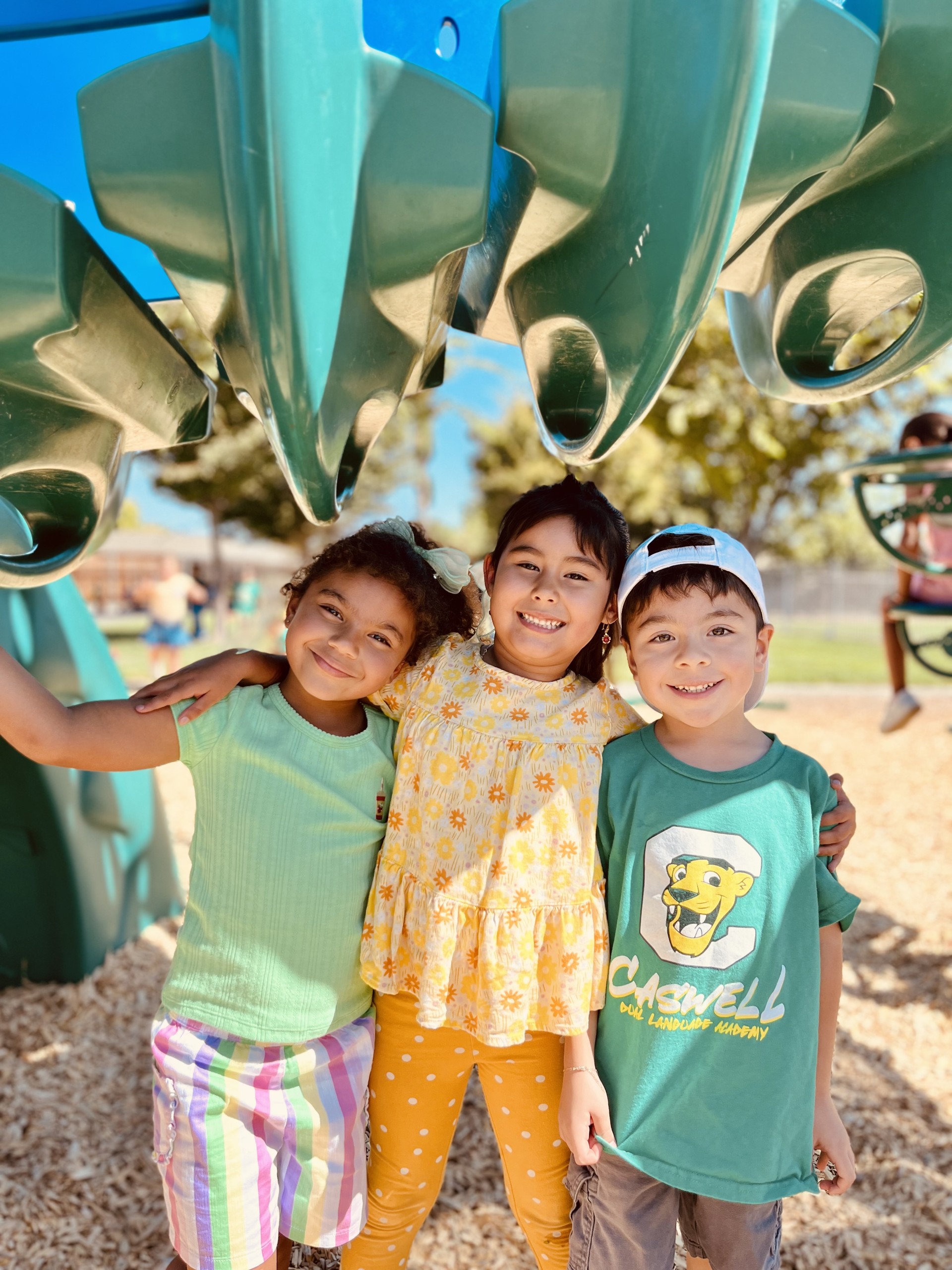 Picture of 3 kindergarten students standing side by side hugging