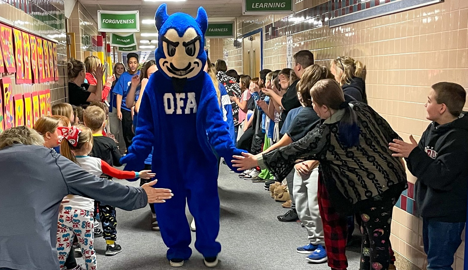 devil mascot gives students high fives in the hall
