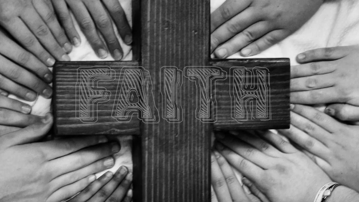 black and white photo of hands touching cross that says faith on it