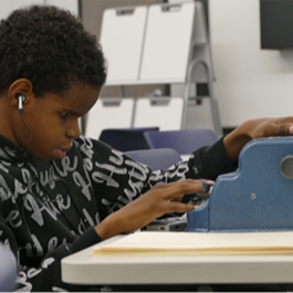 little kid student learning how to cut some pieces of papers