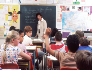 student-raising-hand-in-classroom-teacher-watches