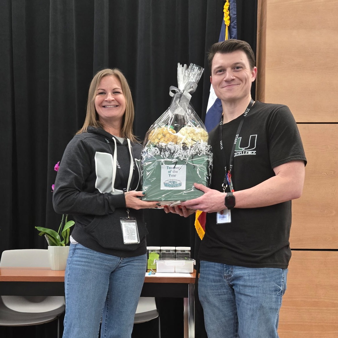 Joe Mortali smiling holding gift box for receiving of teacher of the year, standing next to Utley Middle School principal, smiling