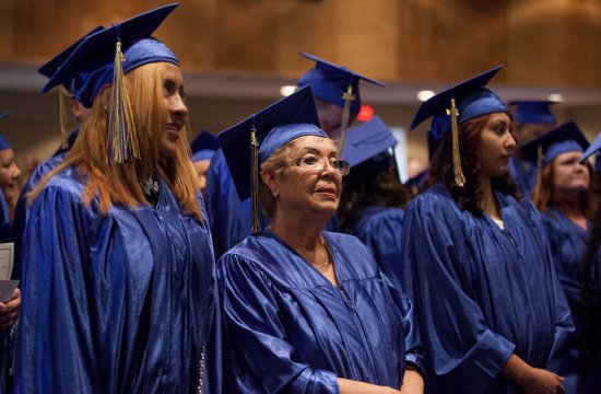 Adult students standing in caps and gowns