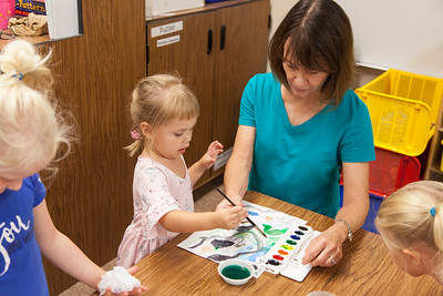 teacher helping a preschool student paint